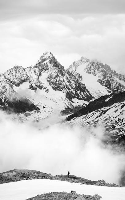 Black and white photo of a person standing on top of a mountain
